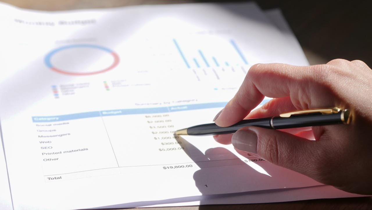 I nostri Servizi Hand holding pen, analyzing budget with charts and graph paper.